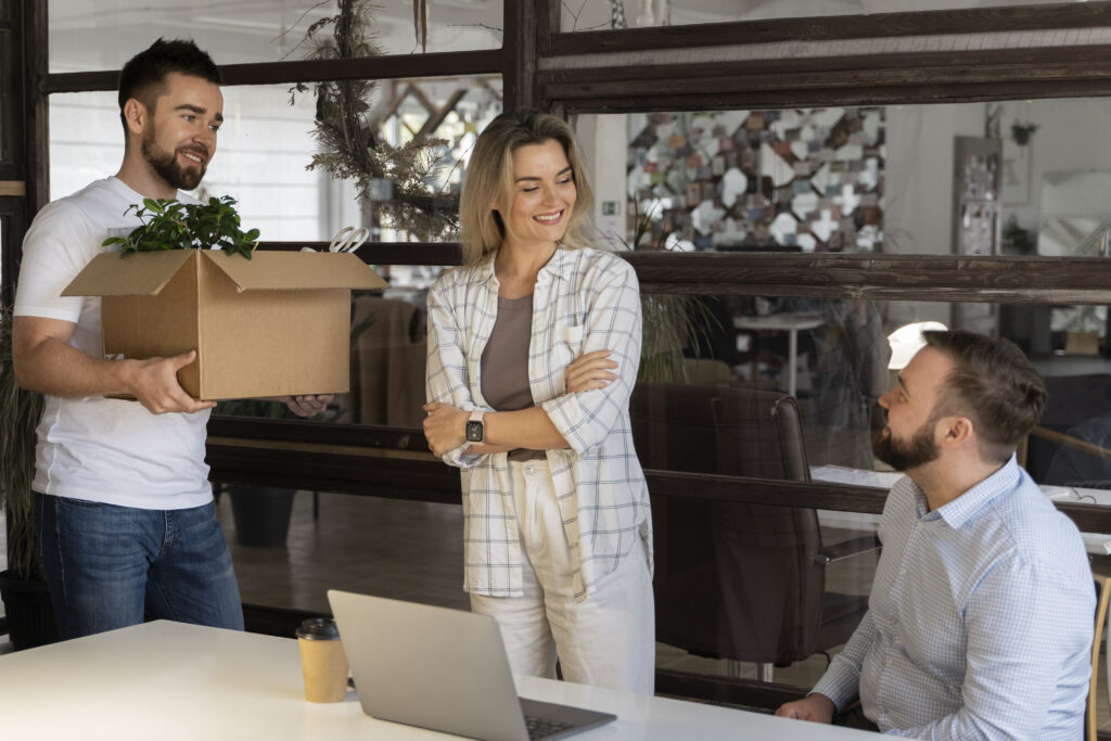 Persona llevando pertenencias en caja de cartón como parte de una mudanza de oficina