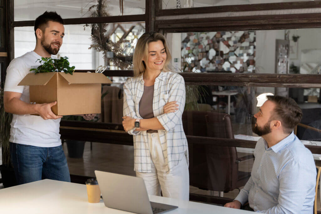 Persona llevando pertenencias en caja de cartón como parte de una mudanza de oficina